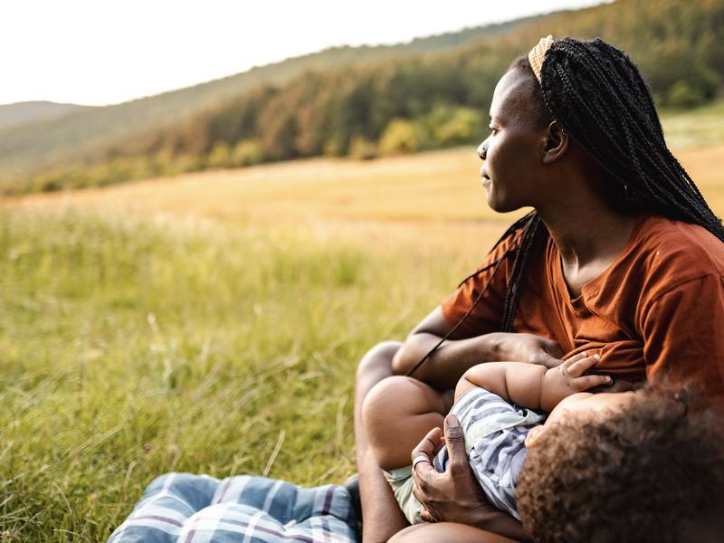Woman breastfeeding an infant in a sunny meadow